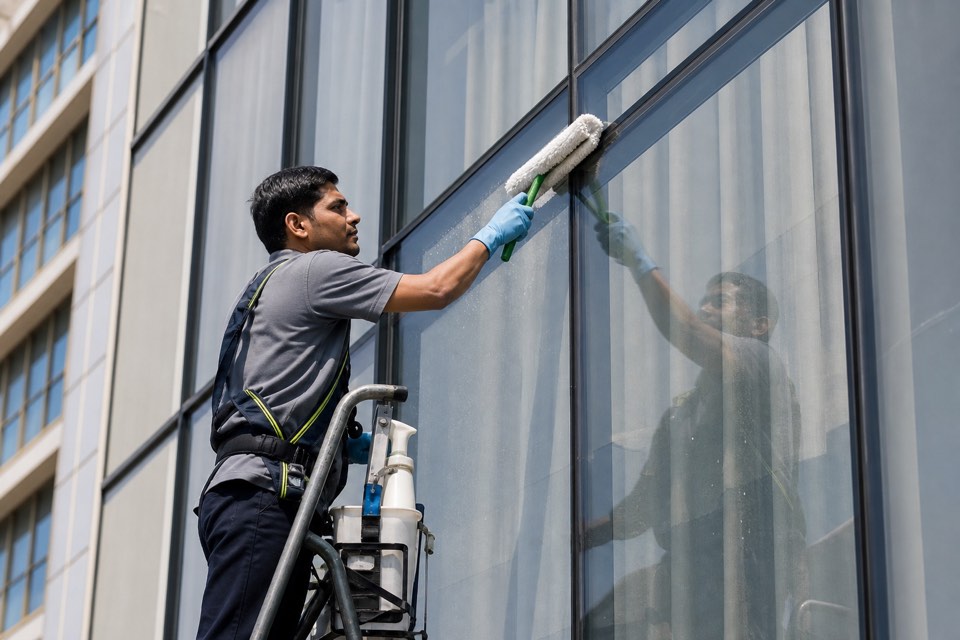 Technician cleaning commercial window panes on institutional building